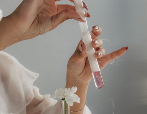 Woman with Manicure Holding Test Tubes, and White Flowers in the Glass